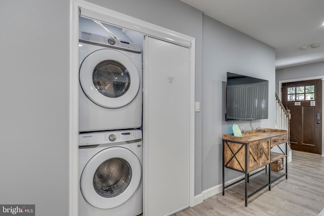 washroom with stacked washing maching and dryer, baseboards, and light wood-style floors