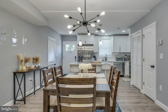 dining area featuring a chandelier, a toaster, light wood finished floors, and baseboards