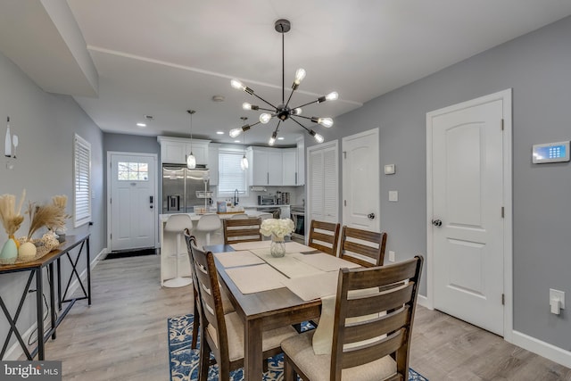 dining room featuring light wood-type flooring, baseboards, and a chandelier