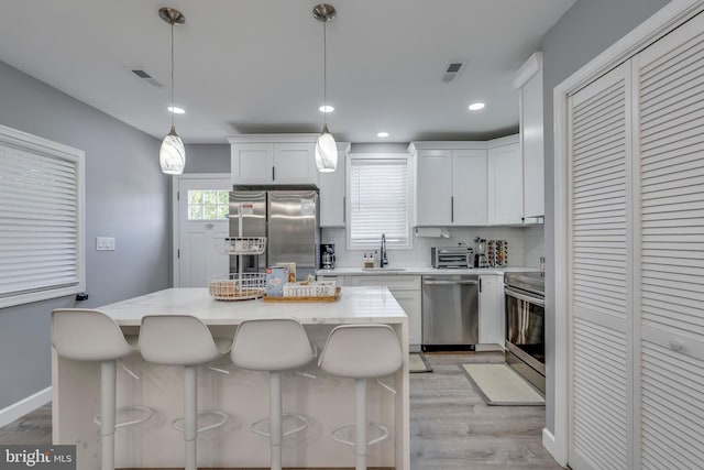 kitchen featuring white cabinetry, appliances with stainless steel finishes, and decorative light fixtures