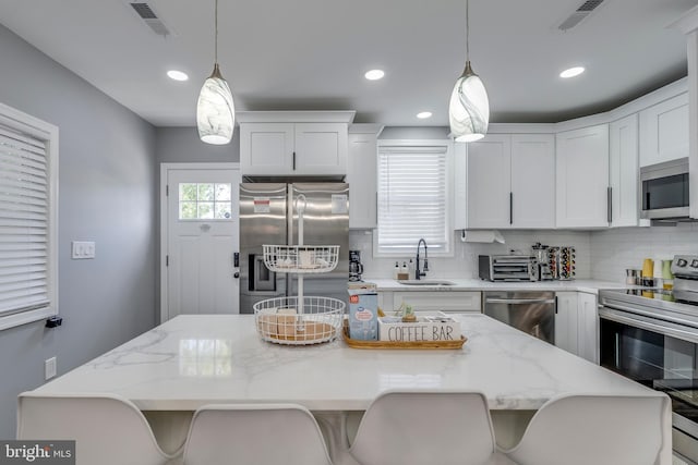 kitchen with a sink, appliances with stainless steel finishes, a kitchen island, and white cabinets