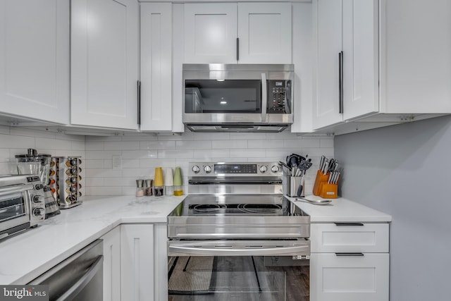 kitchen with stainless steel appliances, decorative backsplash, light stone countertops, and white cabinets