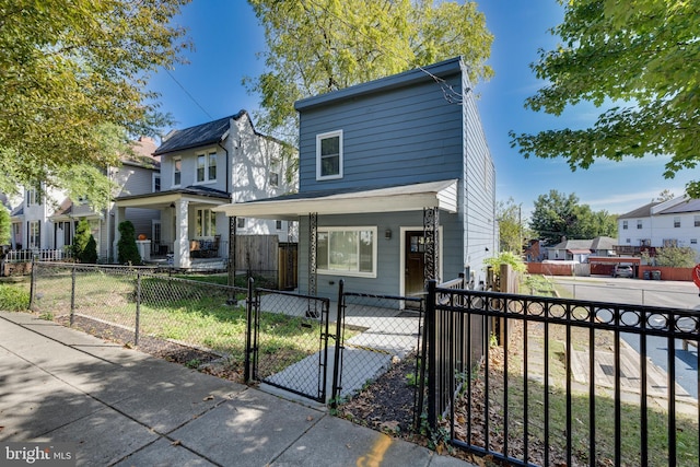 view of front of property with a porch, a fenced front yard, a residential view, and a gate