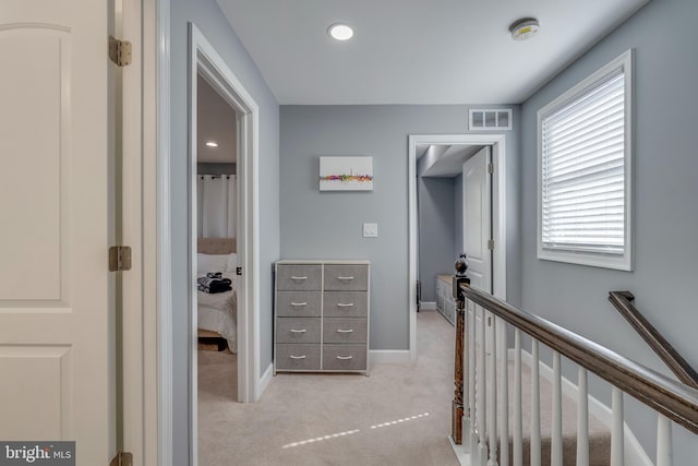 hall with recessed lighting, visible vents, light carpet, an upstairs landing, and baseboards