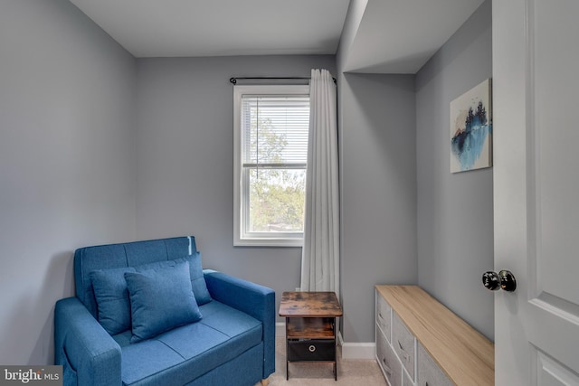 living area featuring light carpet and baseboards