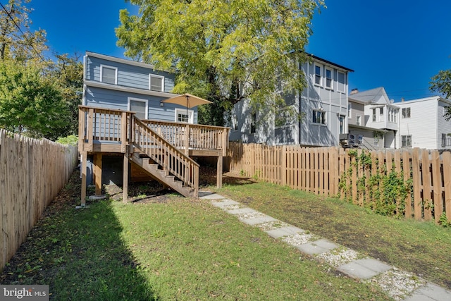 rear view of property featuring a deck, stairway, a lawn, and a fenced backyard