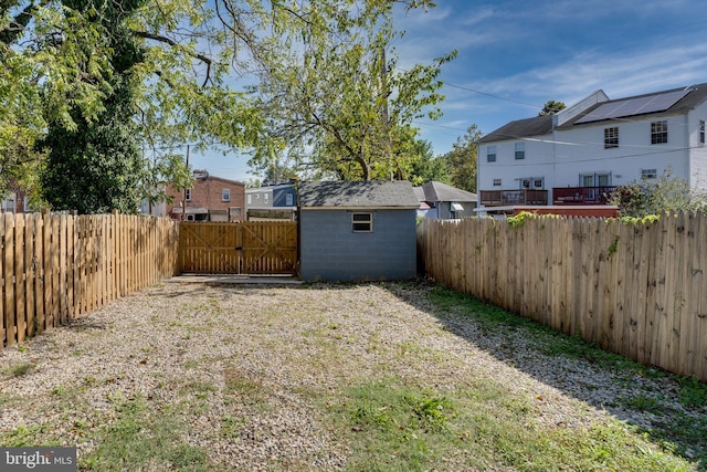 view of yard featuring a storage shed, an outdoor structure, a fenced backyard, and a gate