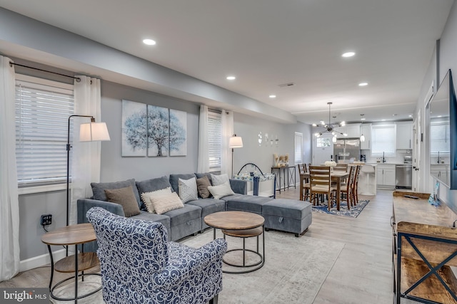 living room featuring an inviting chandelier, light wood-style flooring, and recessed lighting