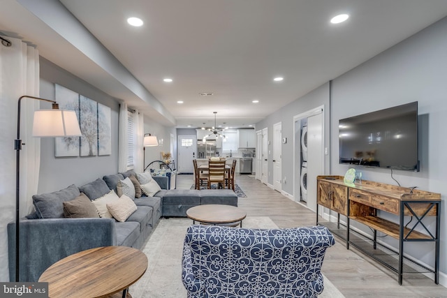 living area featuring light wood-style floors, stacked washer / dryer, and recessed lighting