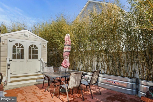 view of patio with outdoor dining space, an outbuilding, and a storage unit