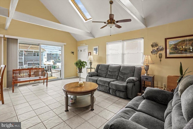 living room featuring light tile patterned floors, vaulted ceiling with skylight, and ceiling fan