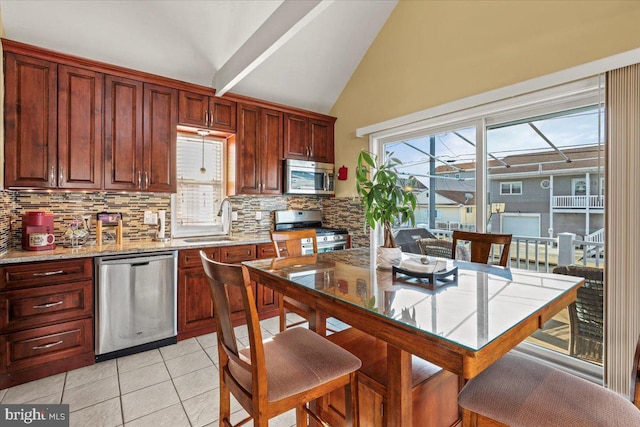 kitchen featuring stainless steel appliances, backsplash, light tile patterned flooring, vaulted ceiling, and a sink