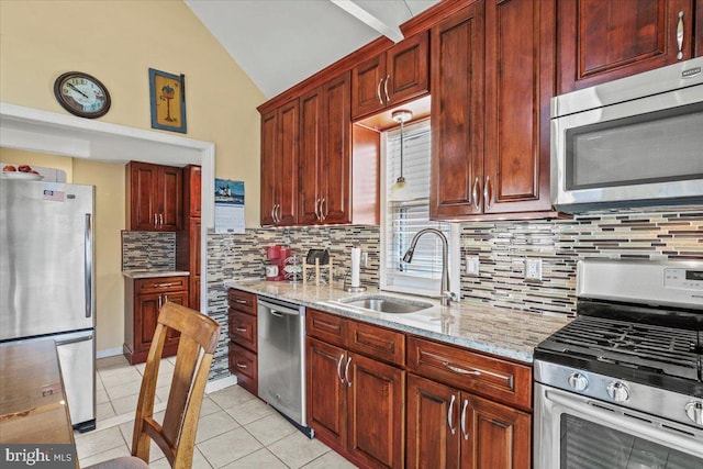 kitchen featuring light stone counters, light tile patterned floors, stainless steel appliances, lofted ceiling, and a sink