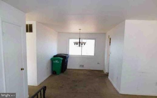 unfurnished dining area featuring carpet floors, an inviting chandelier, and visible vents