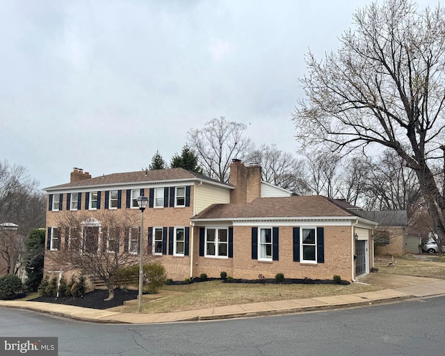 view of front facade with a garage, concrete driveway, brick siding, and a chimney