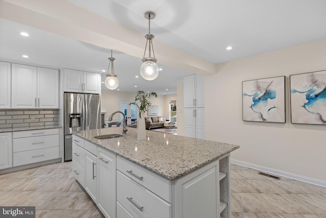 kitchen with a center island with sink, a sink, visible vents, and white cabinets