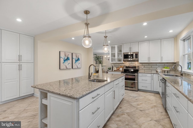 kitchen with stainless steel appliances, white cabinets, a sink, and decorative backsplash