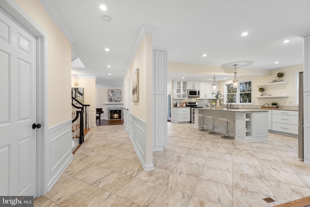 interior space featuring recessed lighting, a decorative wall, crown molding, and wainscoting