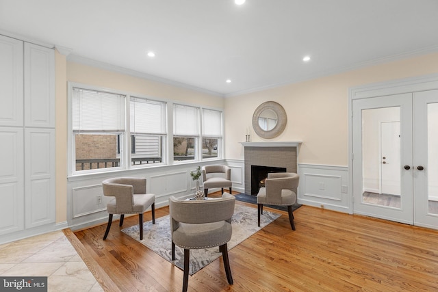 sitting room with light wood-style flooring, a fireplace, and crown molding