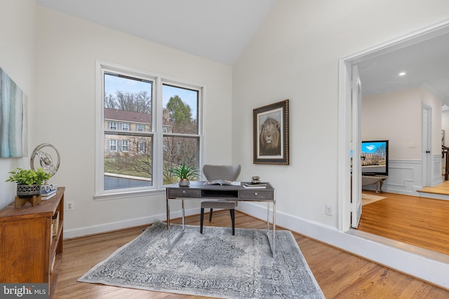 office space featuring lofted ceiling, wainscoting, baseboards, and wood finished floors