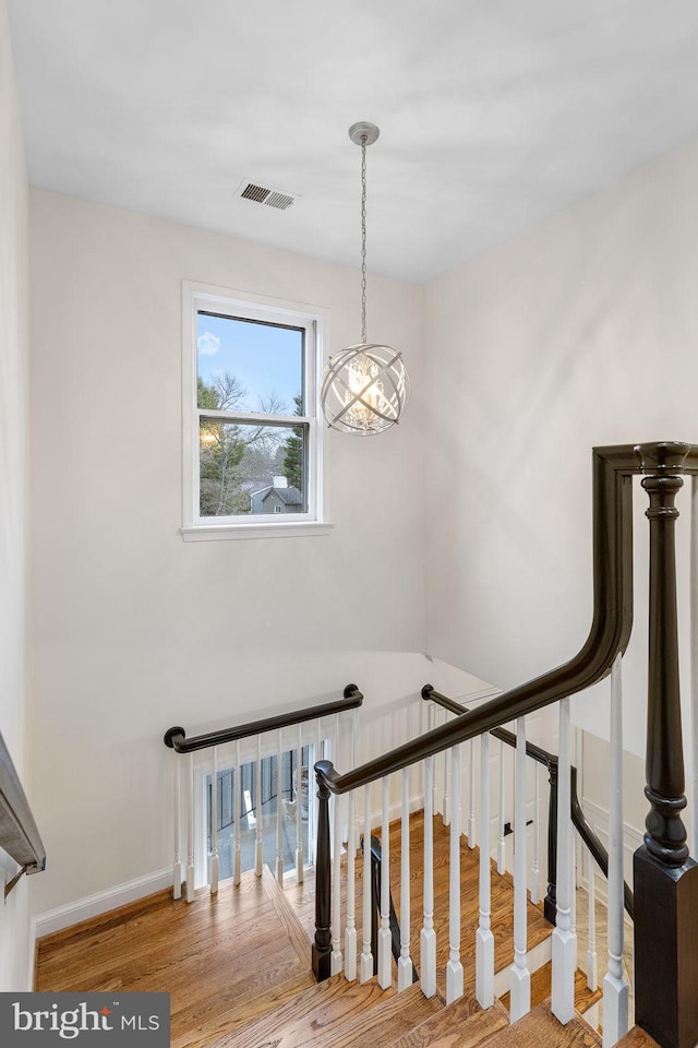 stairway with wood finished floors, visible vents, and baseboards