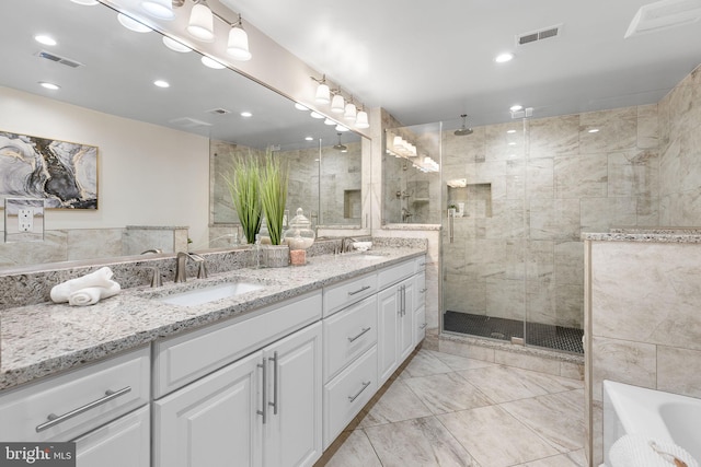 bathroom with visible vents, a sink, and tiled shower