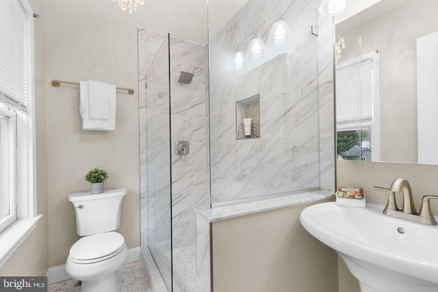 bathroom featuring toilet, baseboards, walk in shower, and a sink