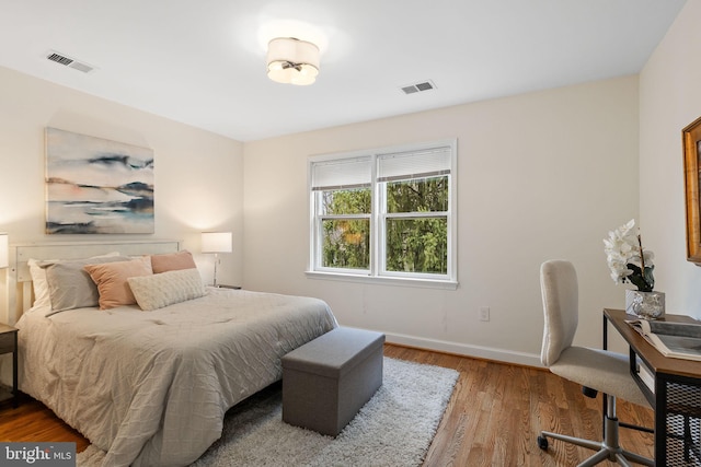 bedroom with visible vents, baseboards, and wood finished floors