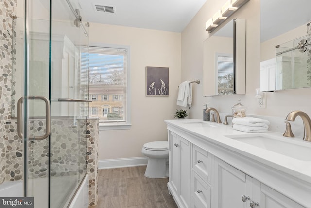 bathroom featuring toilet, double vanity, visible vents, and a sink