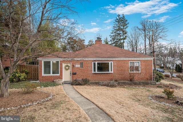 view of front facade with a chimney, fence, a front lawn, and brick siding