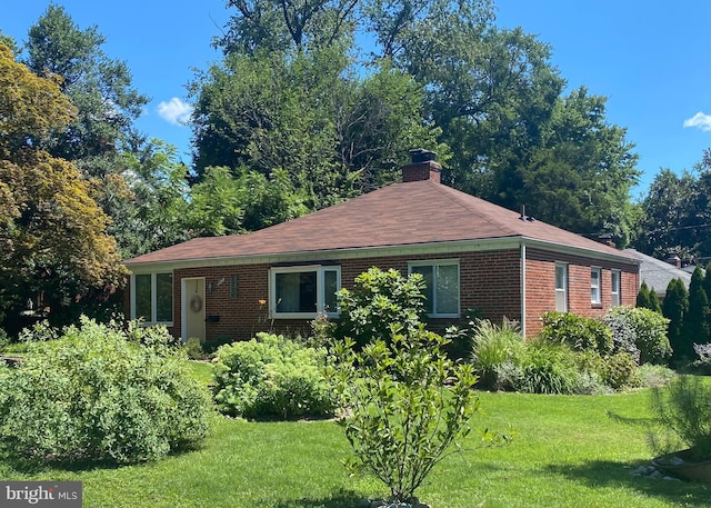 ranch-style house featuring brick siding, a chimney, and a front lawn