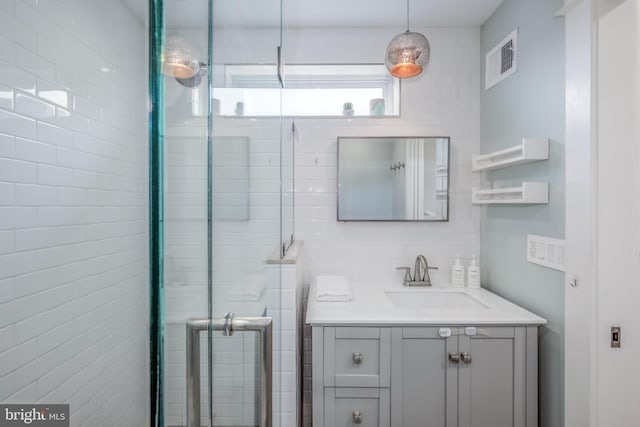 bathroom with decorative backsplash, visible vents, a shower stall, and vanity