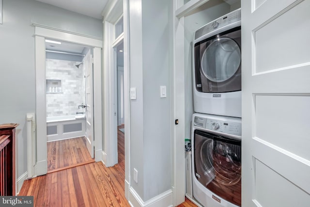 laundry room featuring wood finished floors, stacked washer and clothes dryer, and laundry area