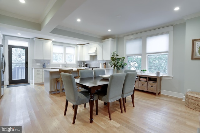 dining space featuring ornamental molding, light wood-style floors, and a healthy amount of sunlight