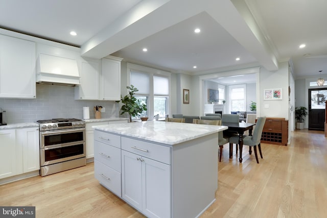 kitchen with white cabinets, double oven range, light wood-type flooring, a center island, and custom range hood