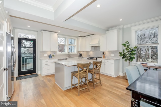 kitchen featuring custom range hood, stainless steel appliances, a center island, and white cabinets