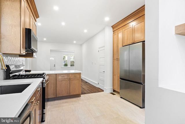 kitchen with brown cabinetry, appliances with stainless steel finishes, a peninsula, light stone countertops, and recessed lighting