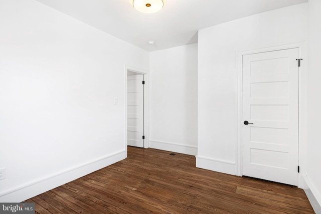 unfurnished room featuring dark wood-style flooring and baseboards