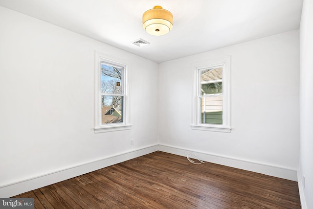 spare room featuring baseboards, visible vents, a wealth of natural light, and wood finished floors