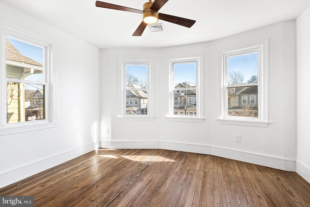 empty room with visible vents, ceiling fan, baseboards, and wood finished floors