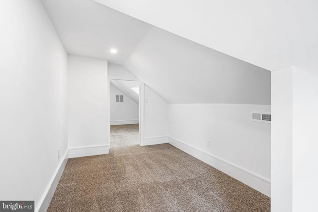 bonus room featuring baseboards, visible vents, vaulted ceiling, and carpet flooring