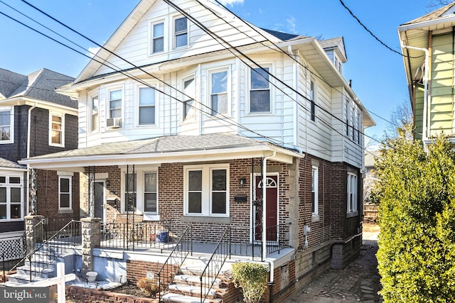 view of front of home featuring covered porch, roof with shingles, cooling unit, and brick siding