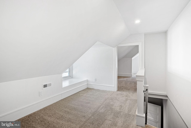 additional living space featuring light carpet, lofted ceiling, visible vents, and baseboards