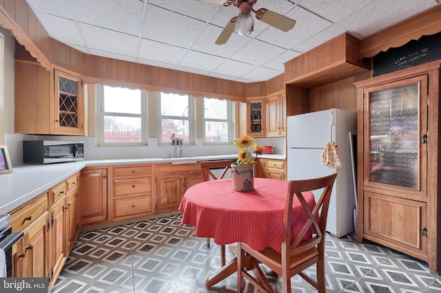 kitchen featuring light countertops, stainless steel microwave, glass insert cabinets, freestanding refrigerator, and a sink