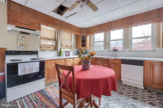 kitchen featuring brown cabinets, white appliances, light countertops, and under cabinet range hood