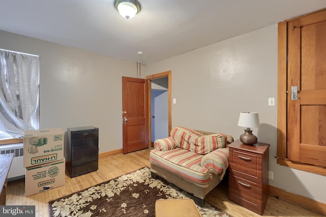 sitting room featuring light wood-type flooring, radiator heating unit, and baseboards