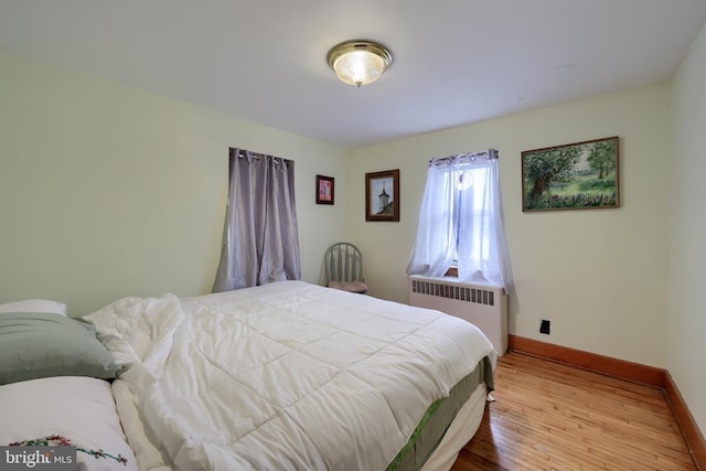 bedroom with baseboards, radiator heating unit, and wood finished floors