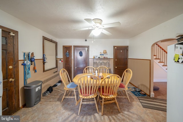 dining room featuring stairs, a ceiling fan, arched walkways, and a textured ceiling