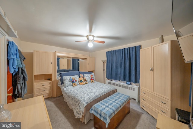 bedroom featuring a ceiling fan, light colored carpet, and radiator heating unit