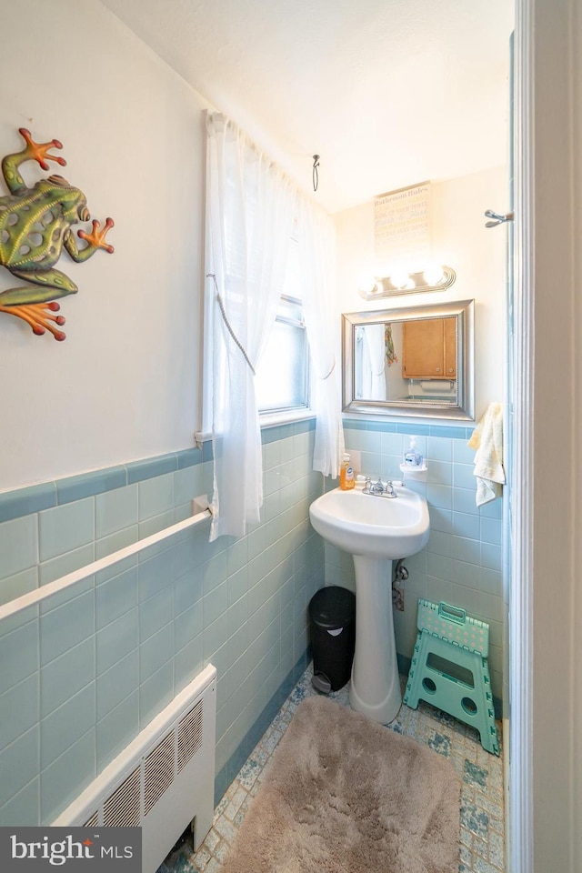 bathroom featuring radiator heating unit, wainscoting, tile patterned floors, tile walls, and a sink